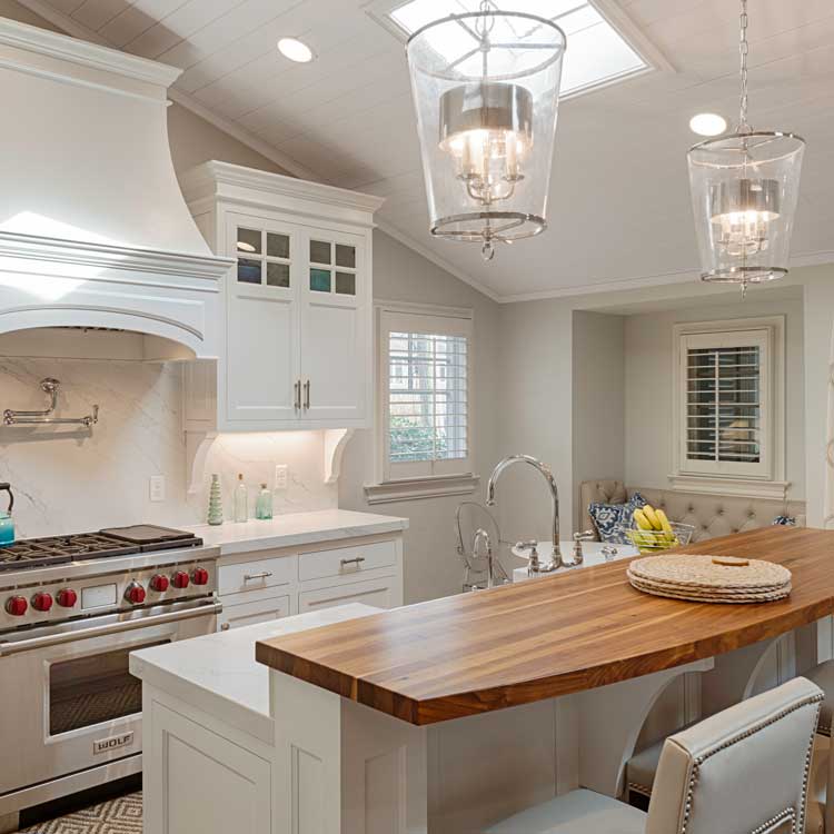 A new kitchen with white cabinets, stone and wood counters and stainless steel appliances