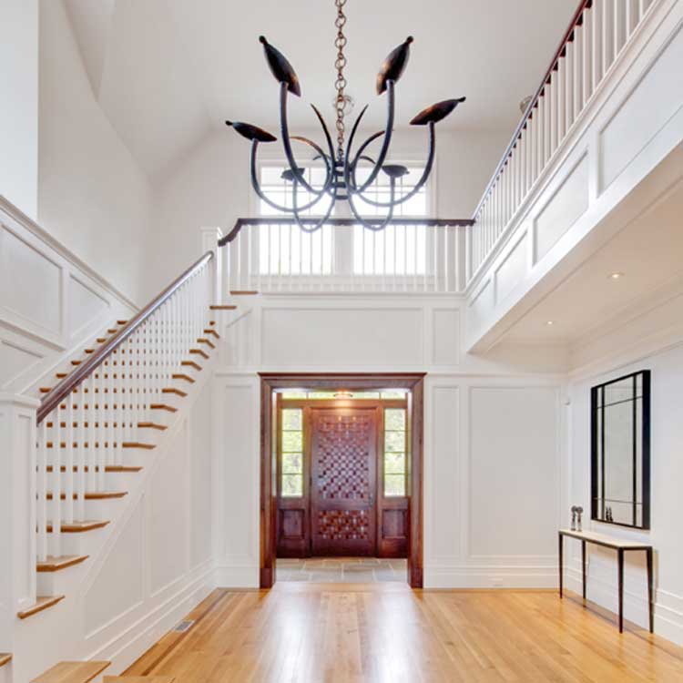 A beautiful home entrance with a dark wood door and grand staircase